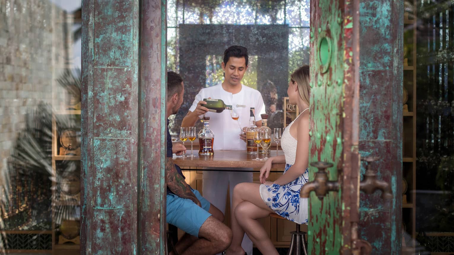 Bartender mixes cocktails for two guests at the bar