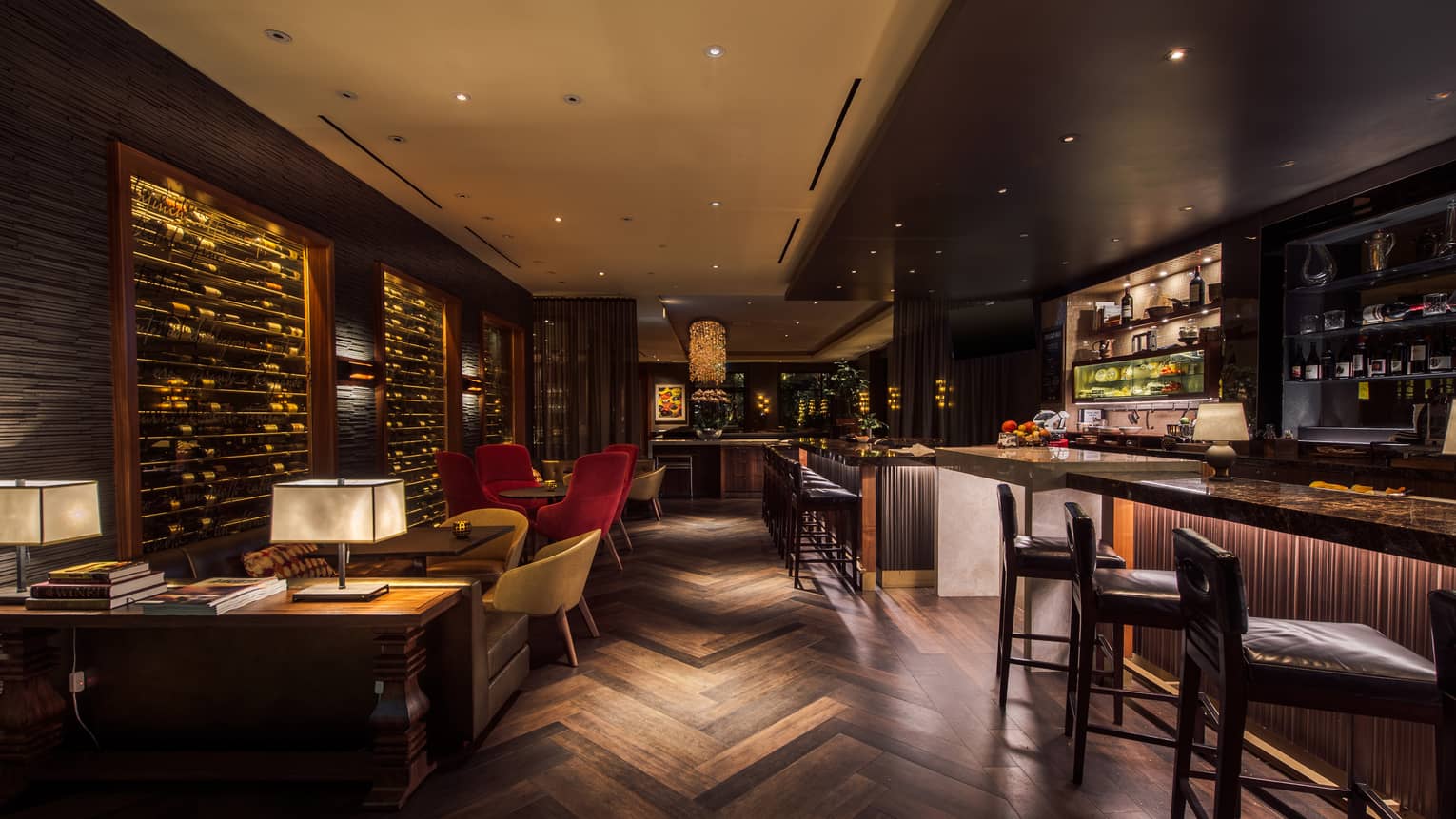 Dimly lit, indoor wine bar with geometric wooden floor, bar, wall of wine bottles