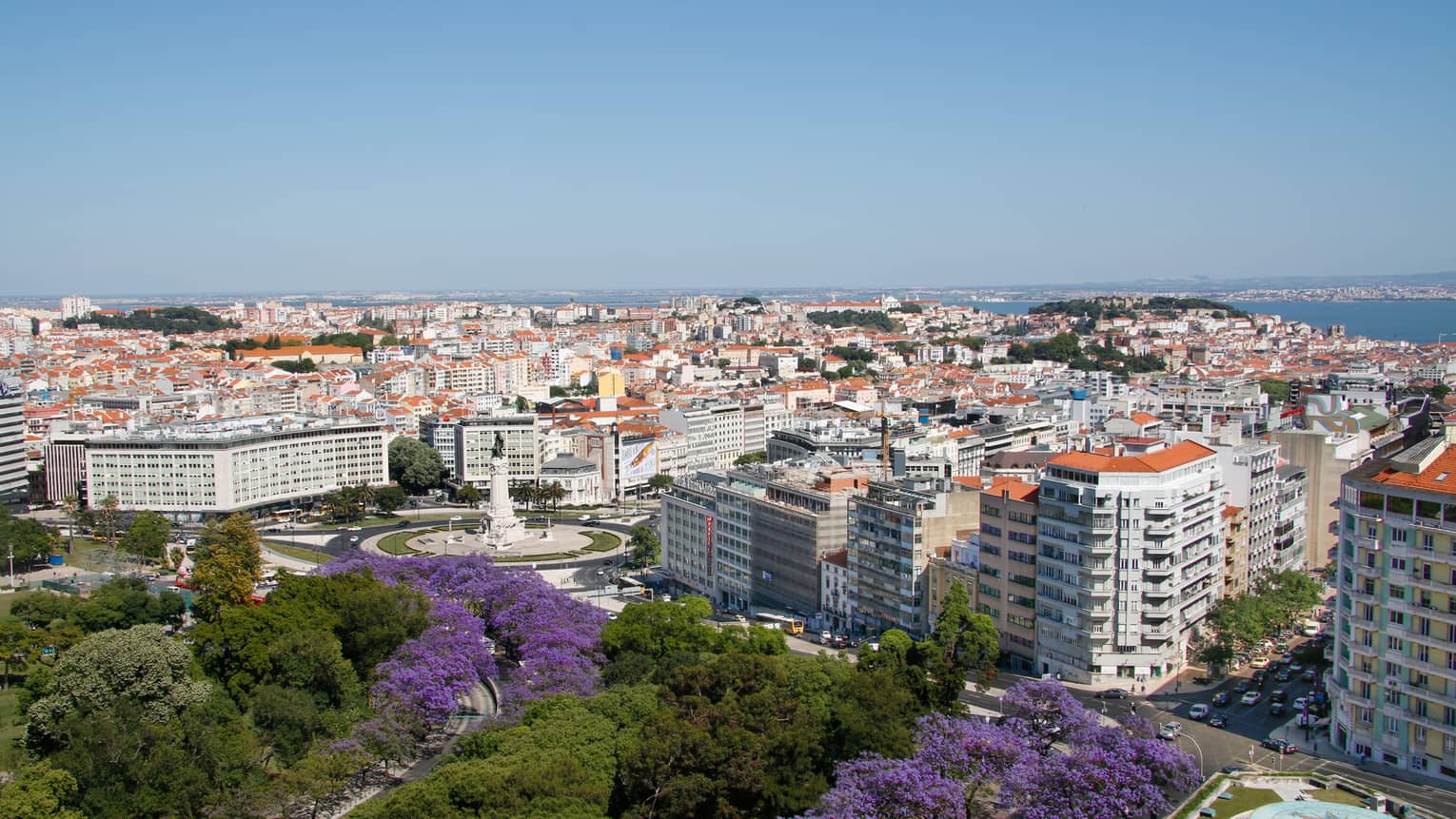 View over sunny Lisbon skyline with gardens, high rise buildings, rooftops