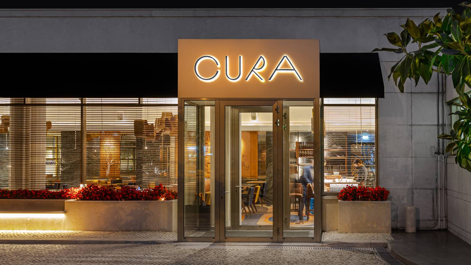 Modern exterior of CURA restaurant illuminated in the evening