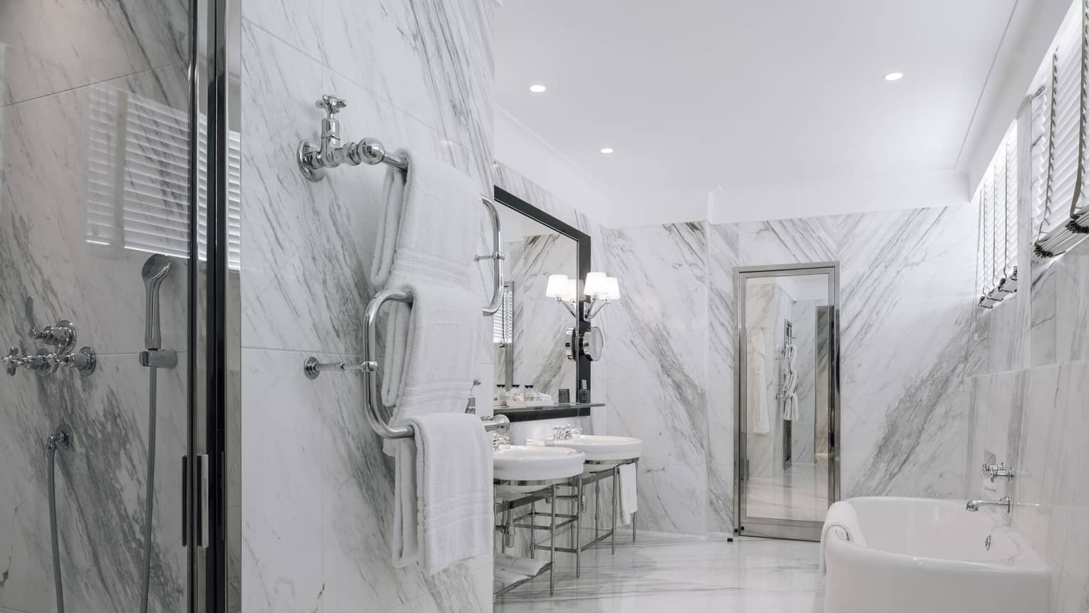 White and grey marble bathroom with two sinks, white tub, walk-in shower