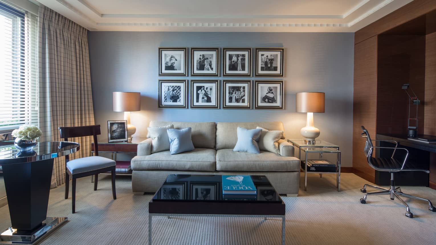 Living room with square coffee table, tan sofa, and blue wall with picture gallery