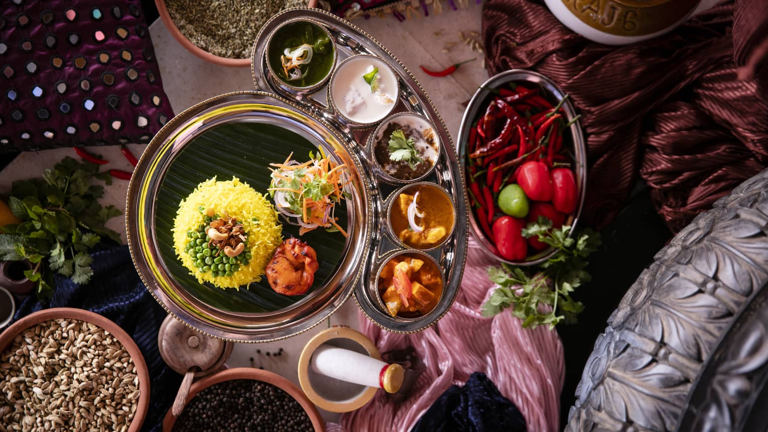 Aerial view of curry dish with rice, bowls of condiments and mortar and pestle