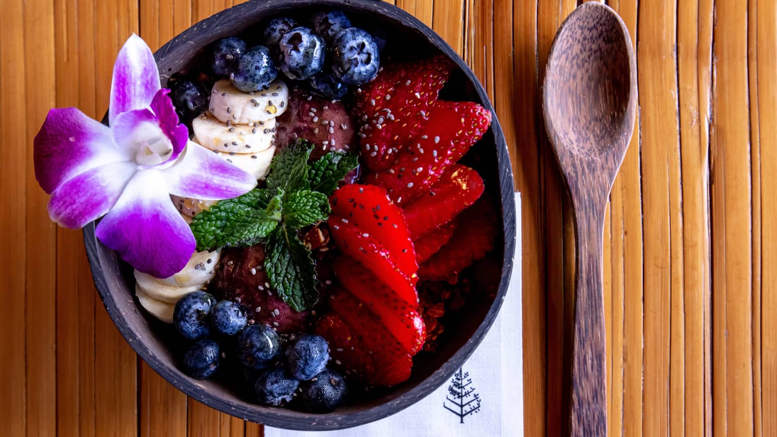 Acai bowl with strawberries, blueberries and a Hawaiian flower