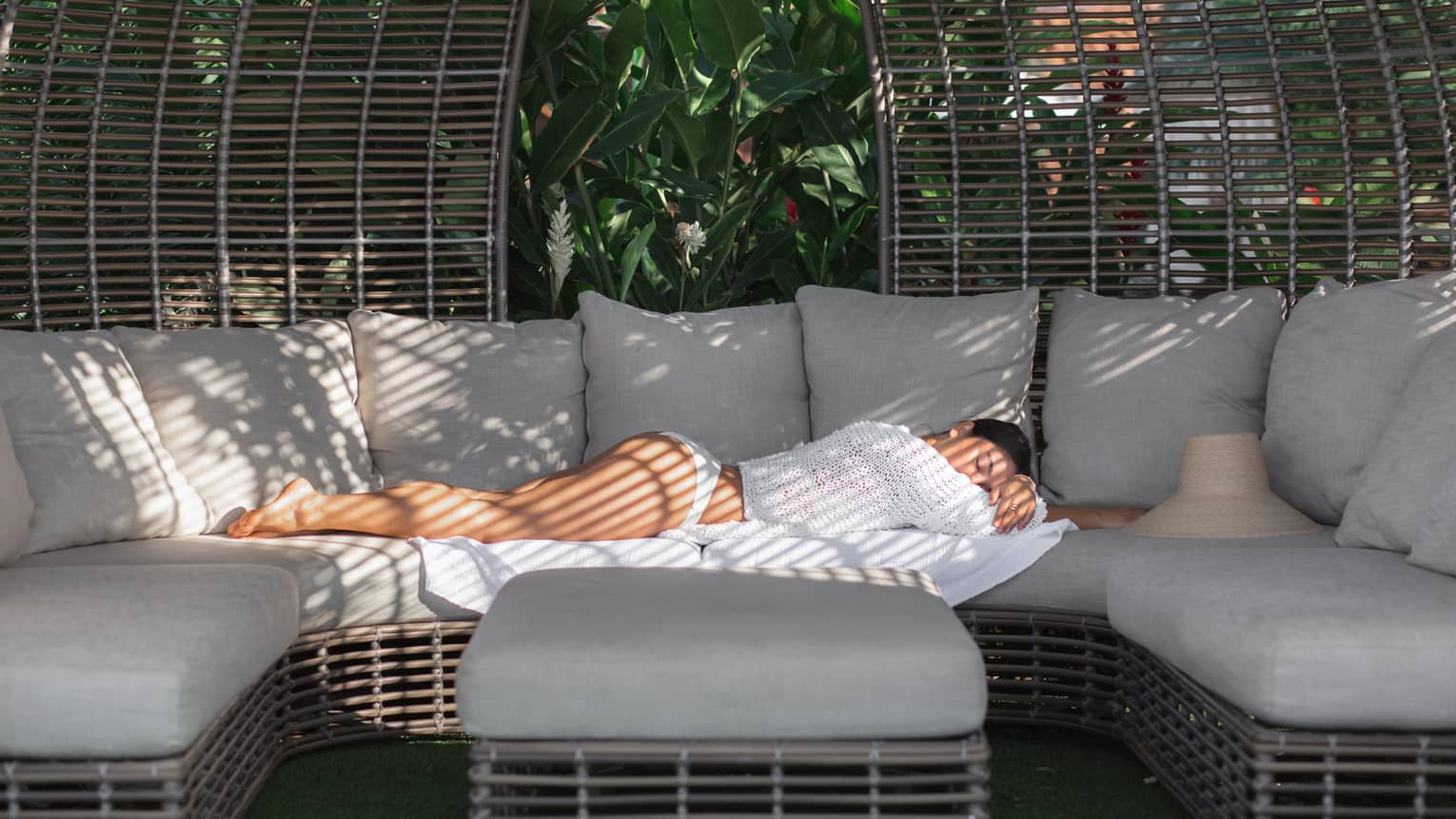 Woman lays on outdoor sofa