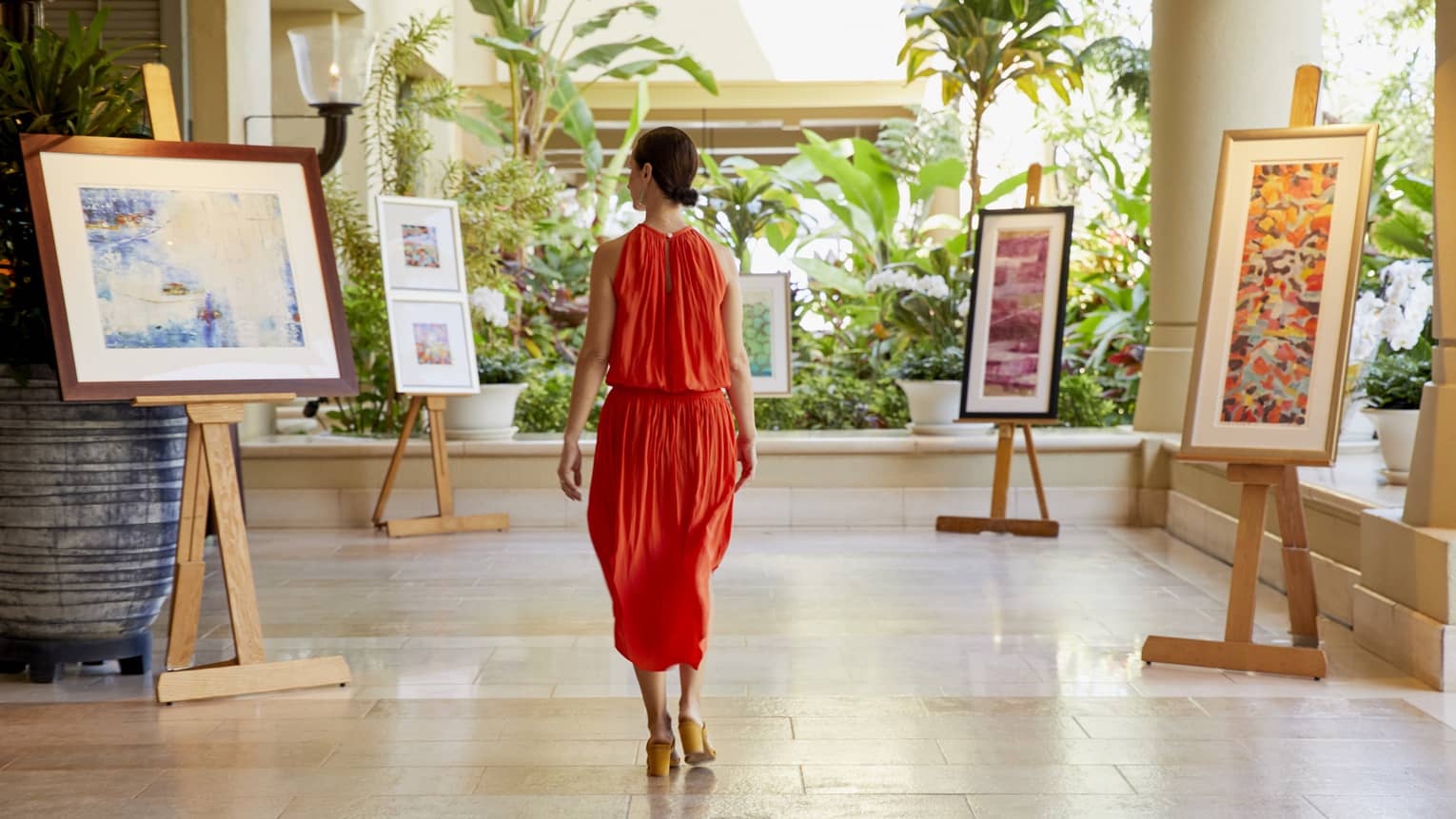 Woman walking through indoor-outdoor room with displayed artwork