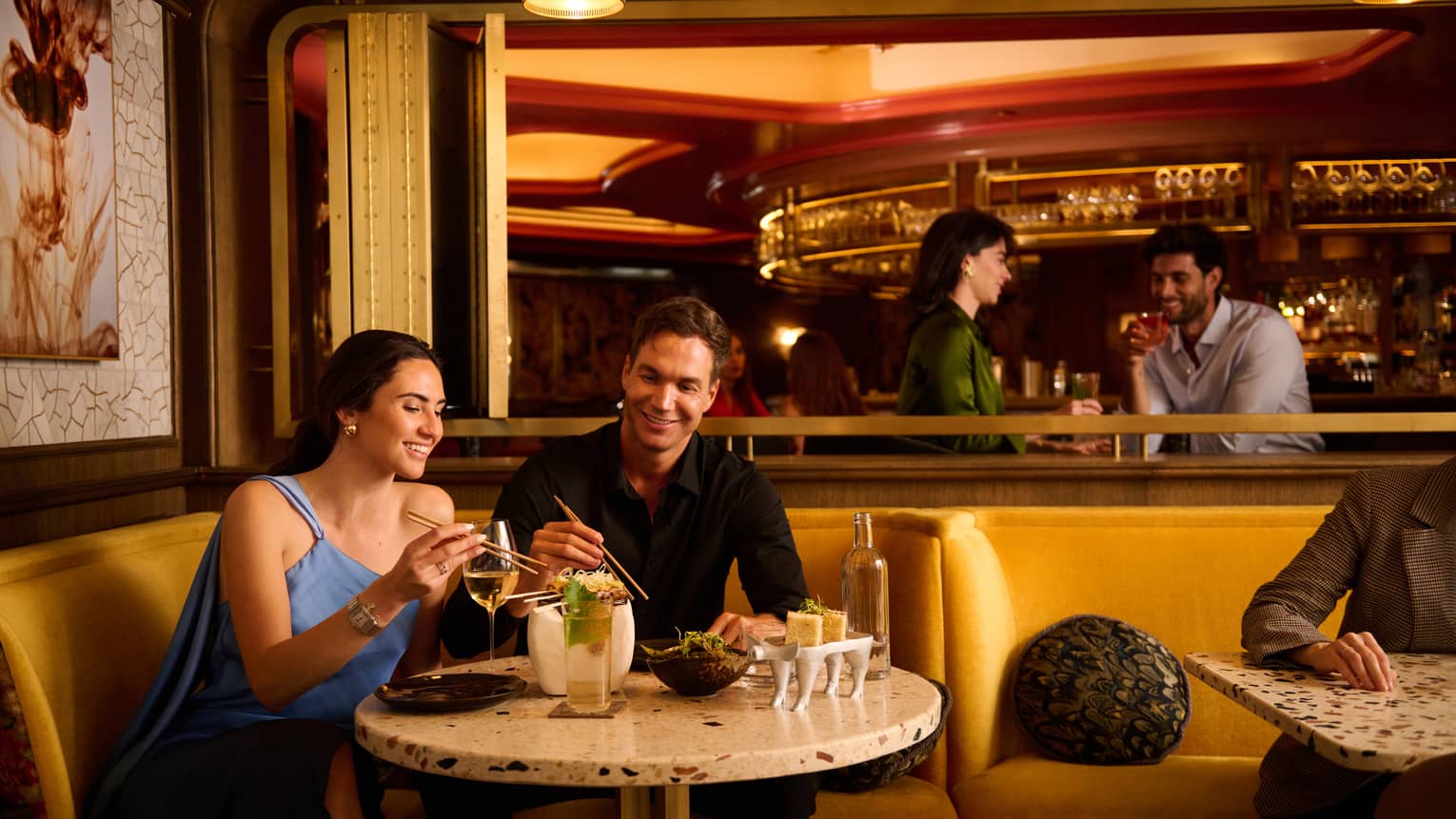 Man and woman sit at restaurant table drinking and eating at Isa Restaurant 
