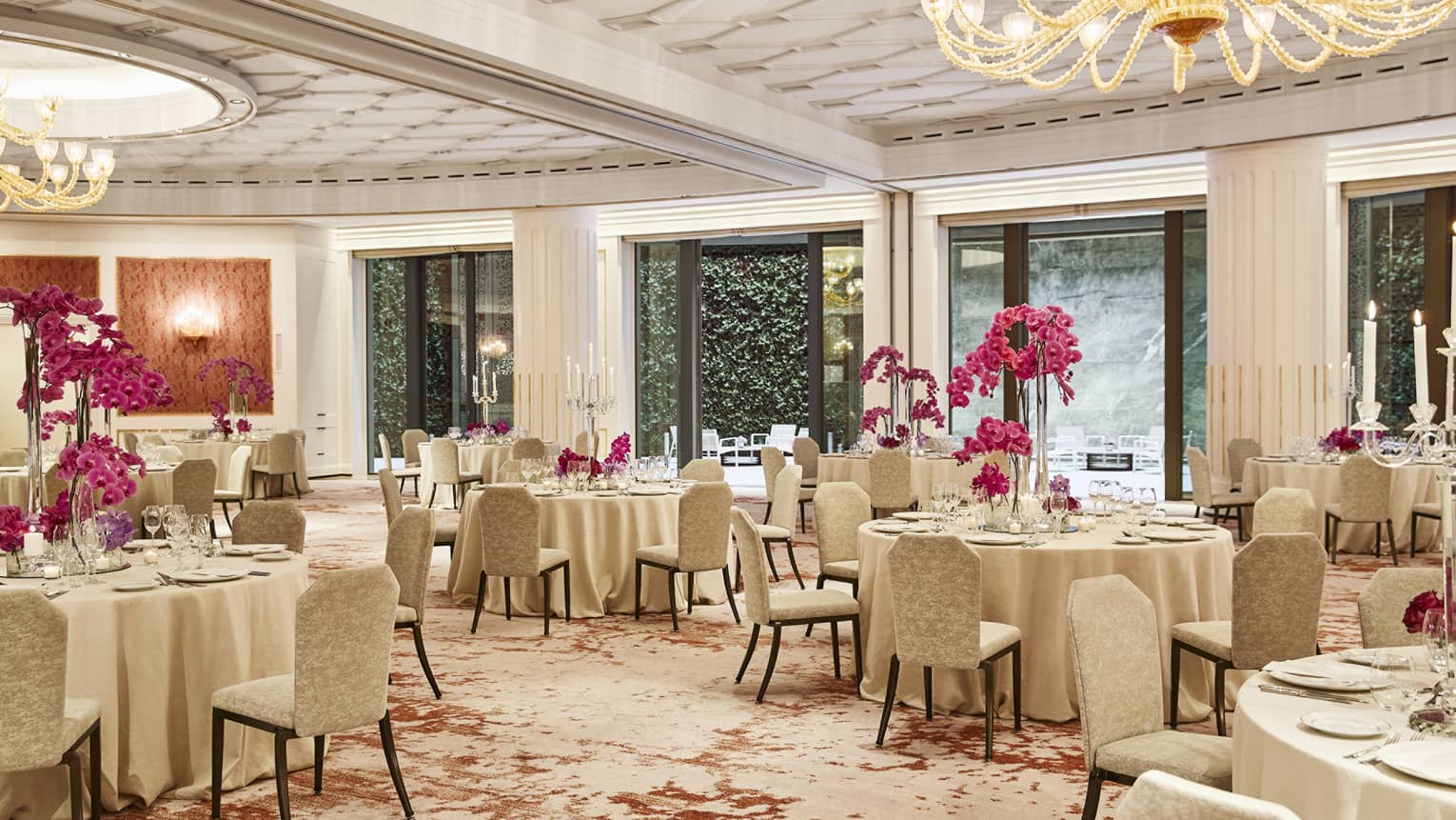 Ballroom with circular banquet tables, gold chandeliers, tall pink centrepieces