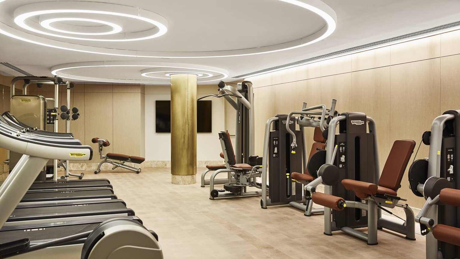 Fitness centre with three treadmills, weight-training machines, modern circular lights on the ceiling