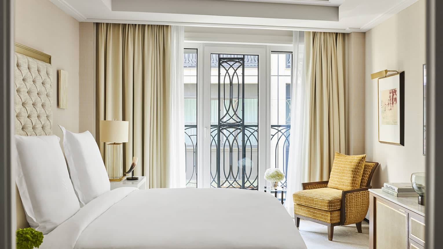 Hotel room with king bed, gold-coloured arm chair and Juliet balcony