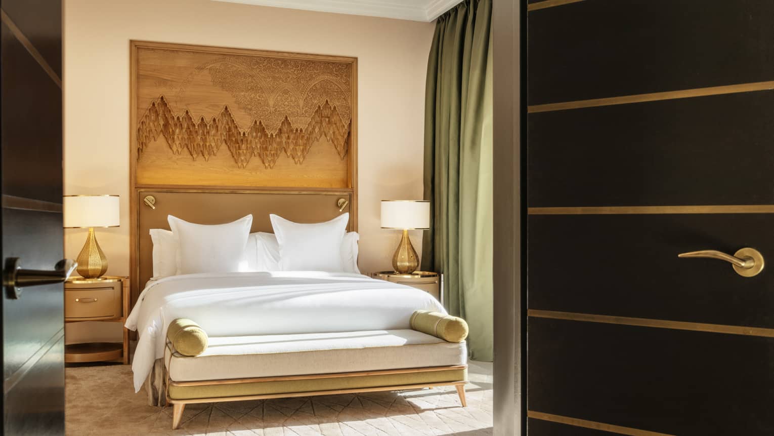 Entrance into a hotel room with king bed and wooden headboard