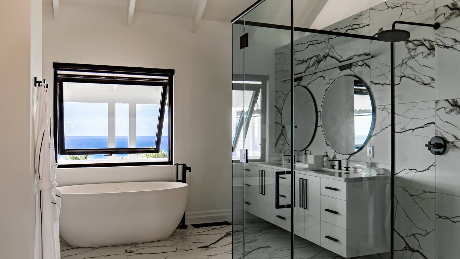 Marble bathroom with large glass shower, oval tub, double vanity and window with sea view
