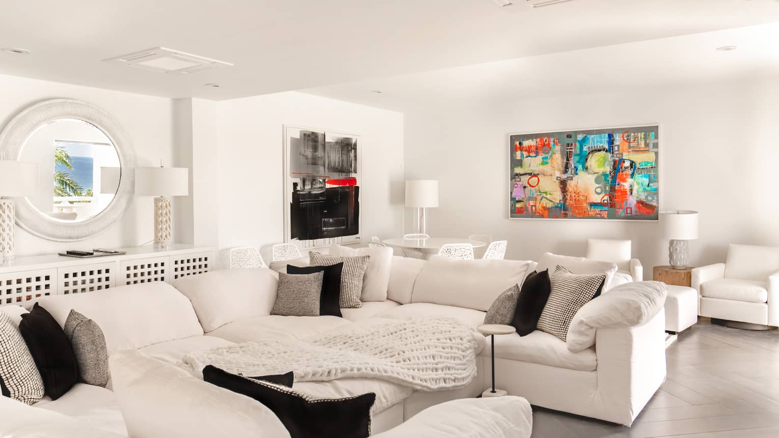 Living room with large u-shape white sofa and colorful artwork on the white walls