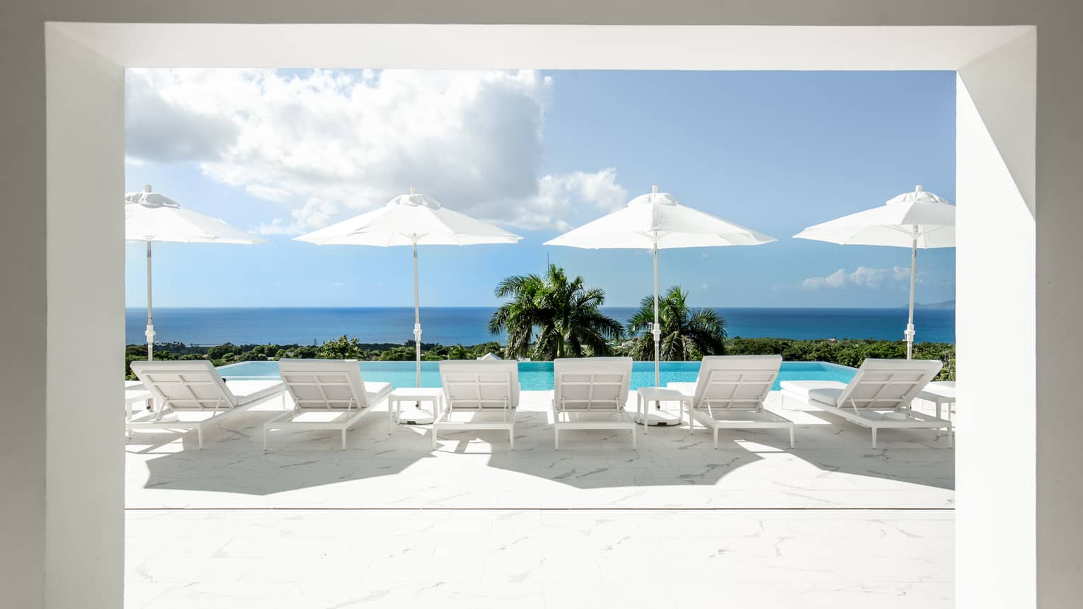 Private pool deck with six lounge chairs, four umbrellas and sea view