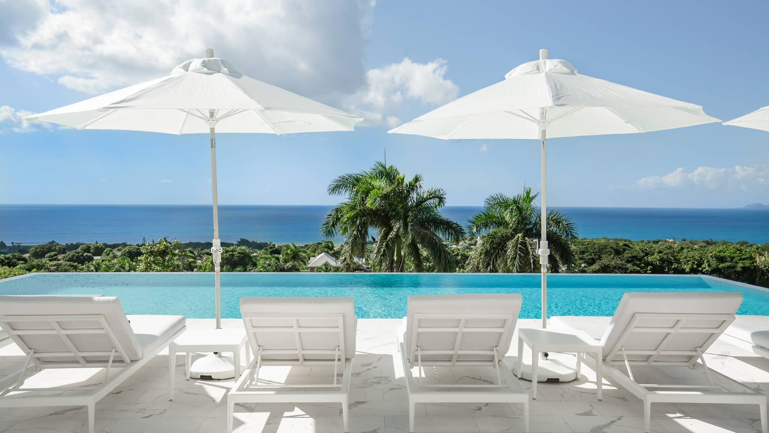 Private pool deck with lounge chairs, umbrellas and sea view