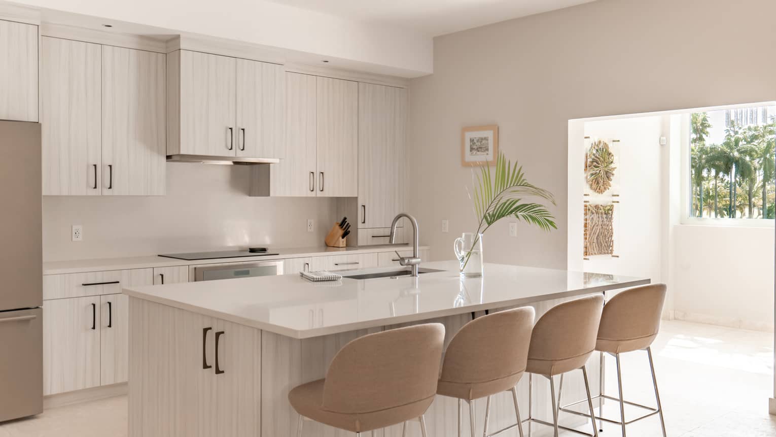 Kitchen with white cupboards, white counters and four taupe counter-height chairs