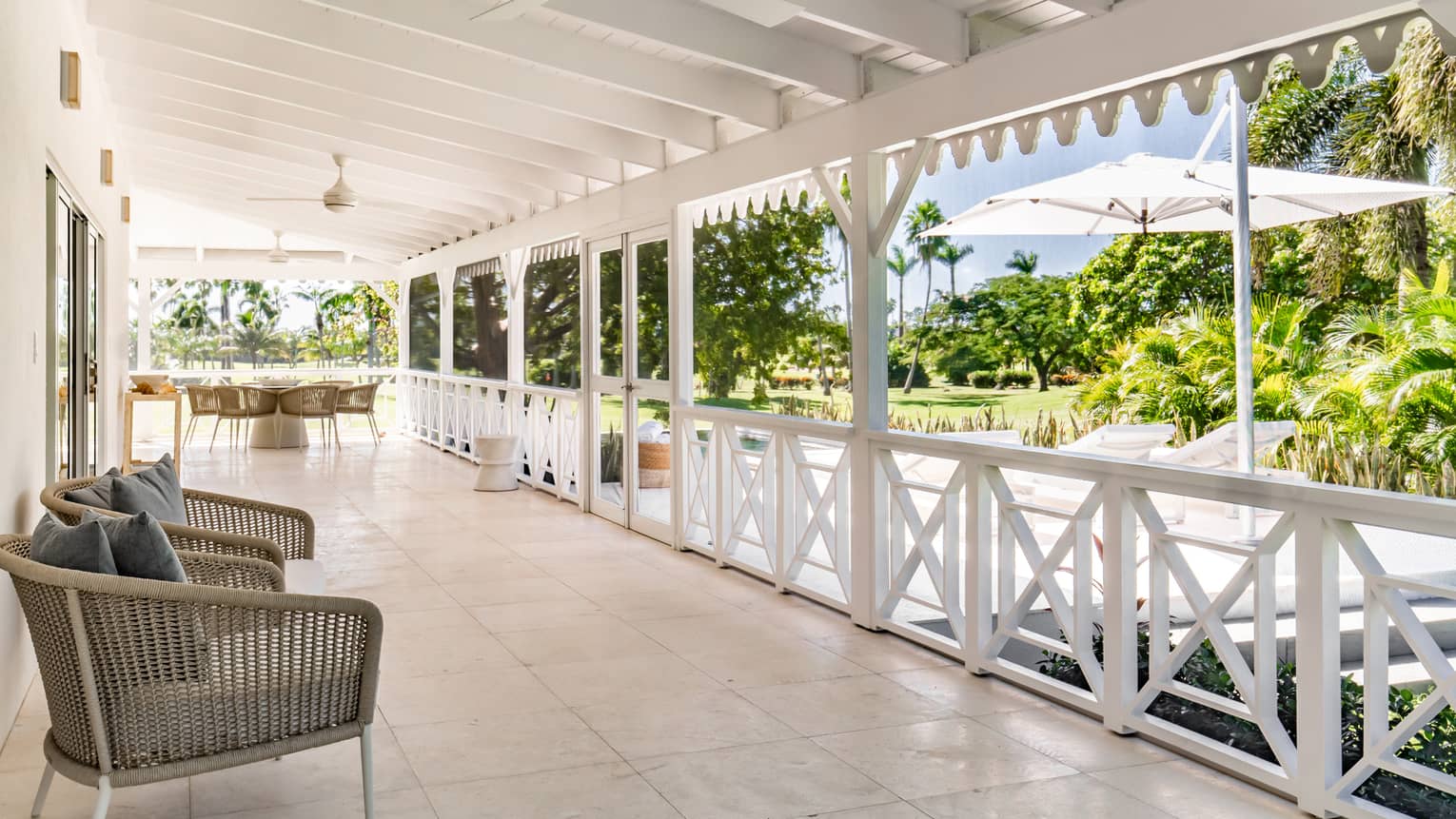 Covered porch of home in Nevis, with arm chairs and a tropical view