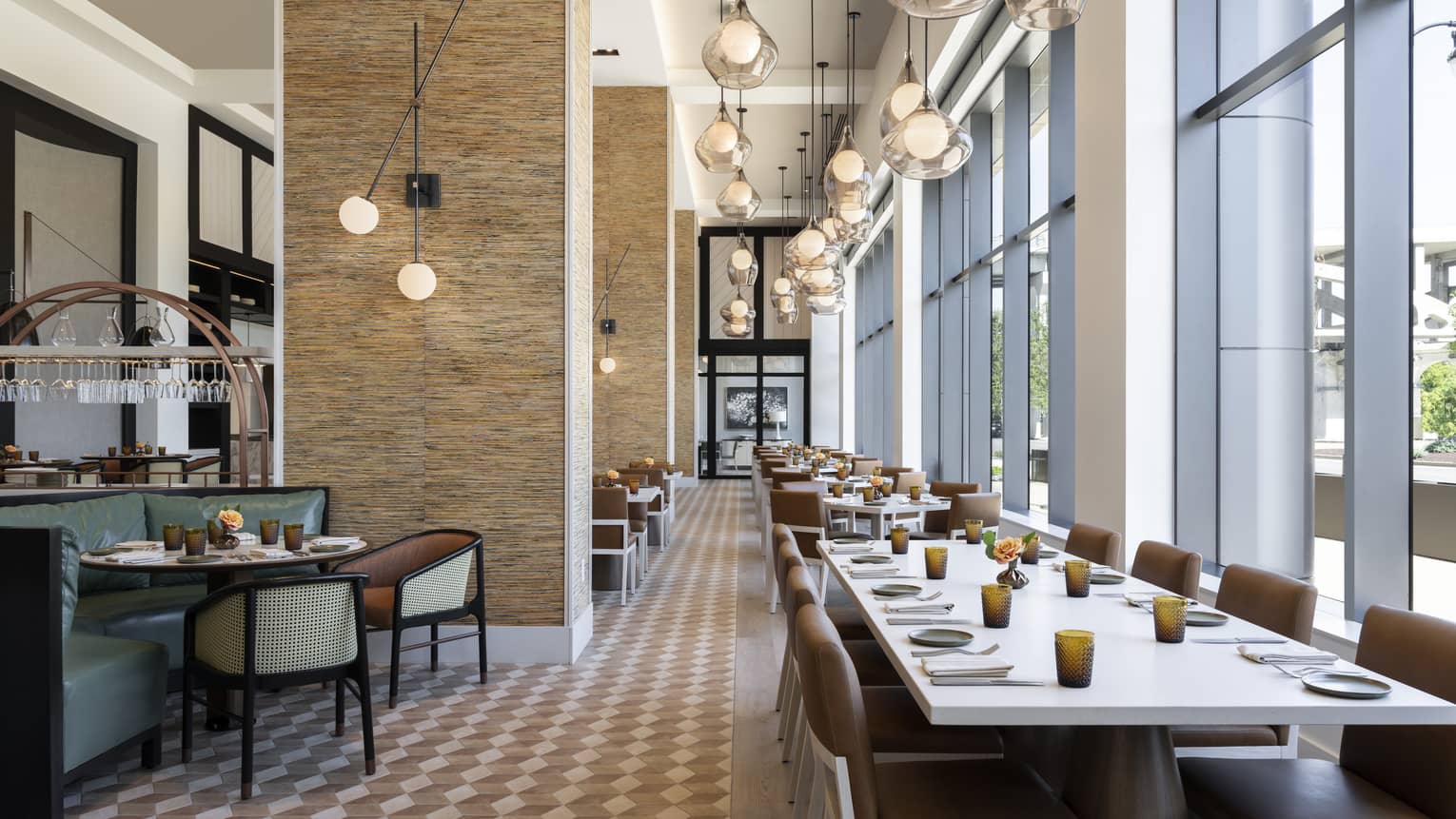 Contemporary indoor restaurant with tables lined along a wall of windows