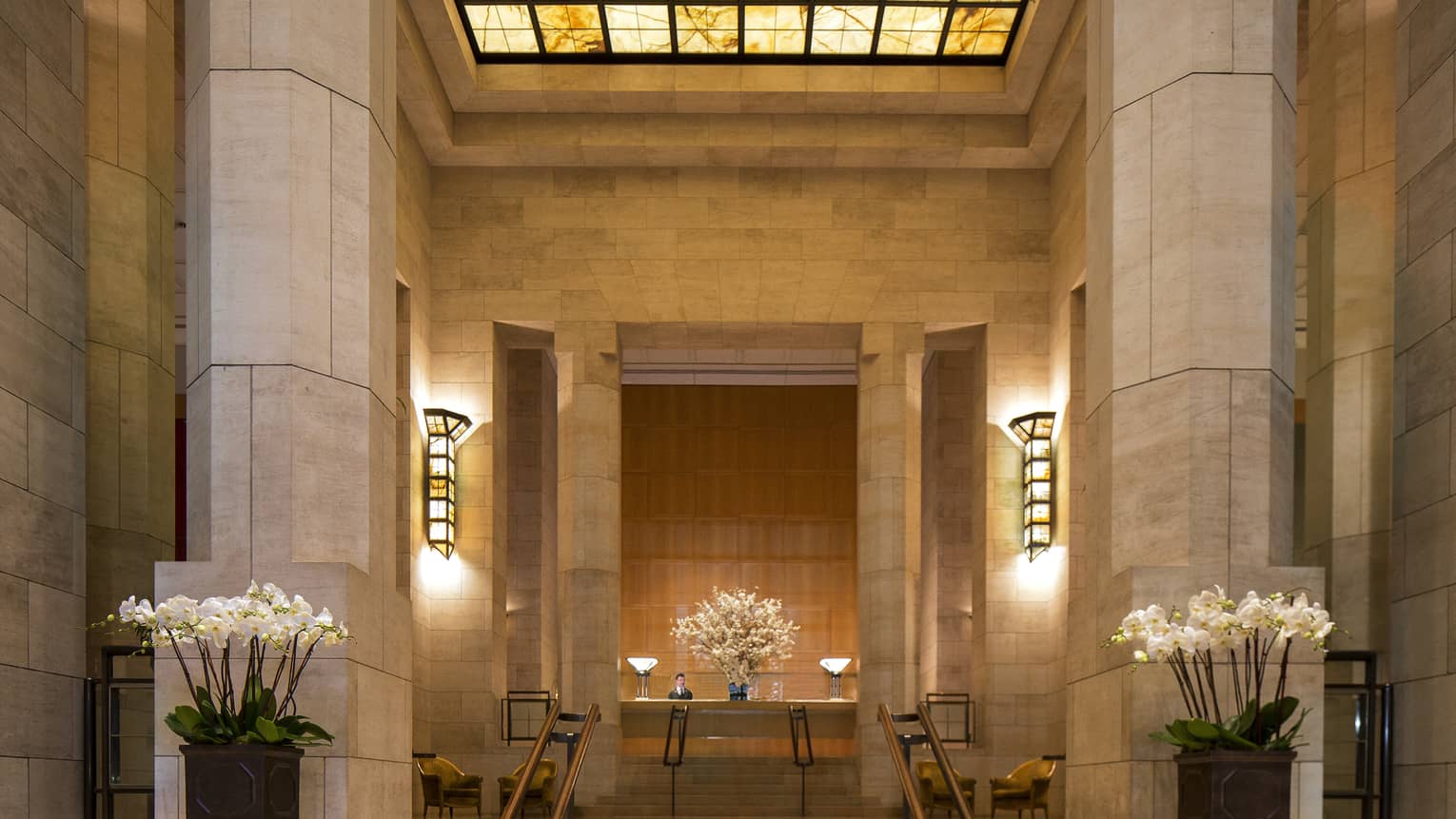 Tall marble columns, steps to hotel reception under amber skylight