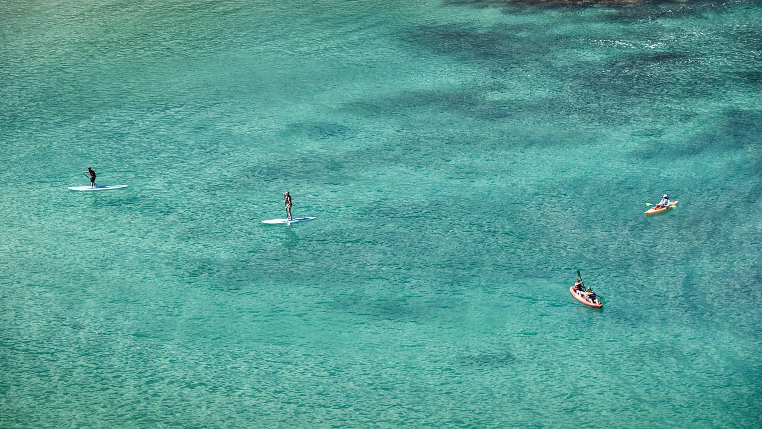 Aerial view of stand-up paddleboarders, boats on lagoon
