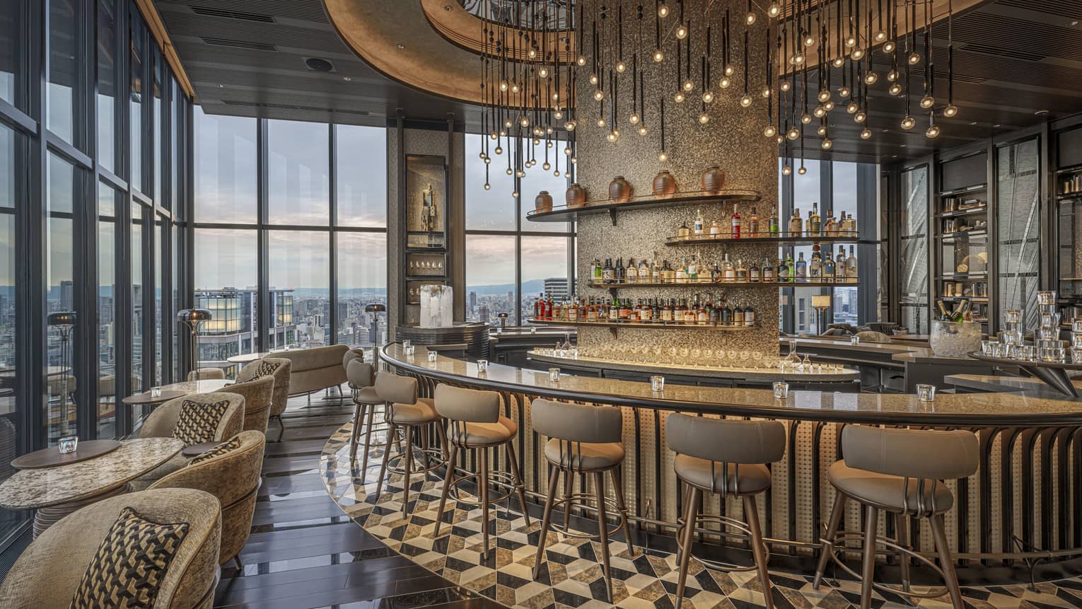 Glamorous indoor hotel bar with curved bar, high-top stools and modern hanging lights, Bar Bota at Four Seasons Hotel Osaka