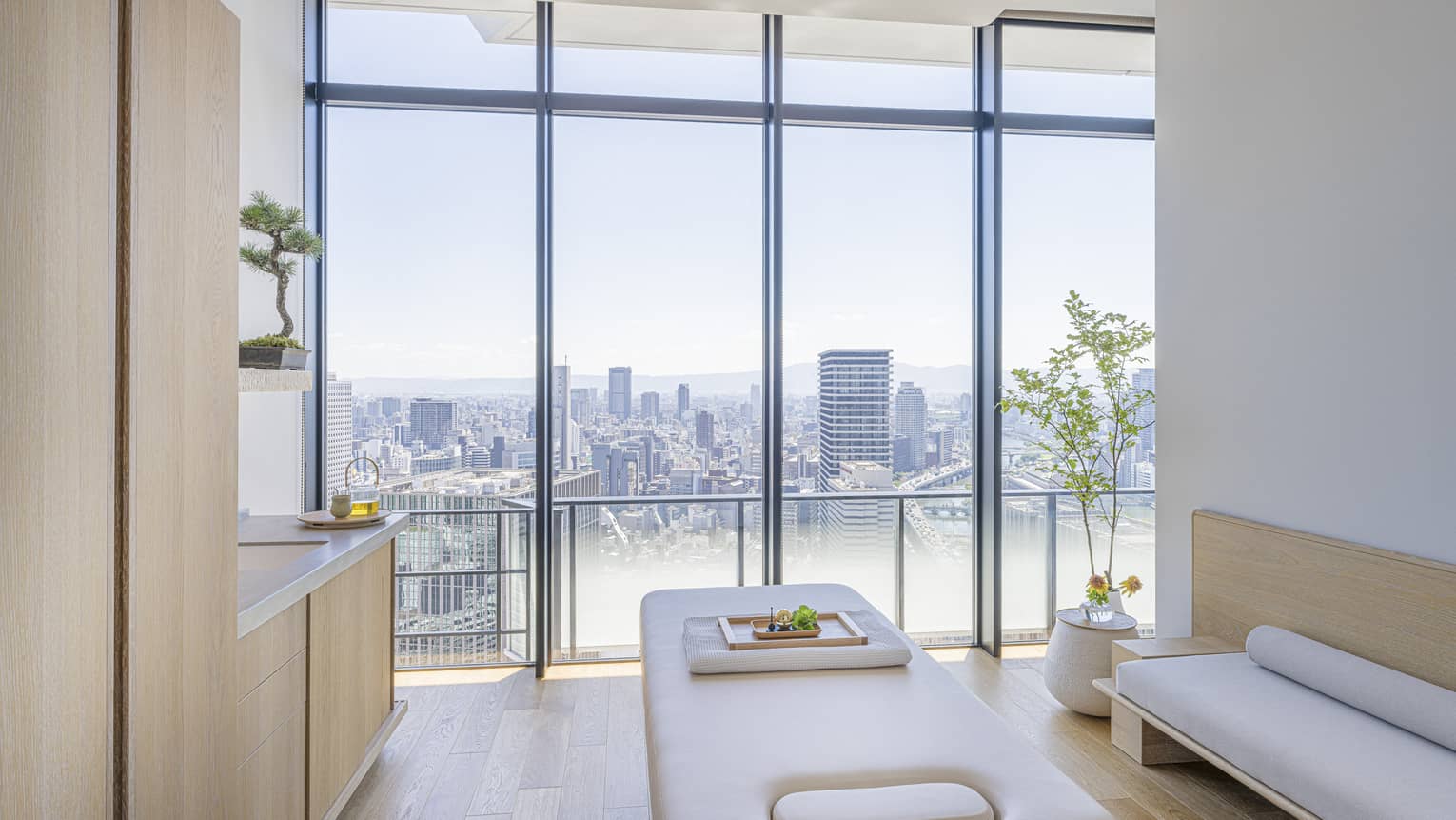 Spa treatment room with light wood cabinets and wall of windows, at Four Seasons Hotel Osaka