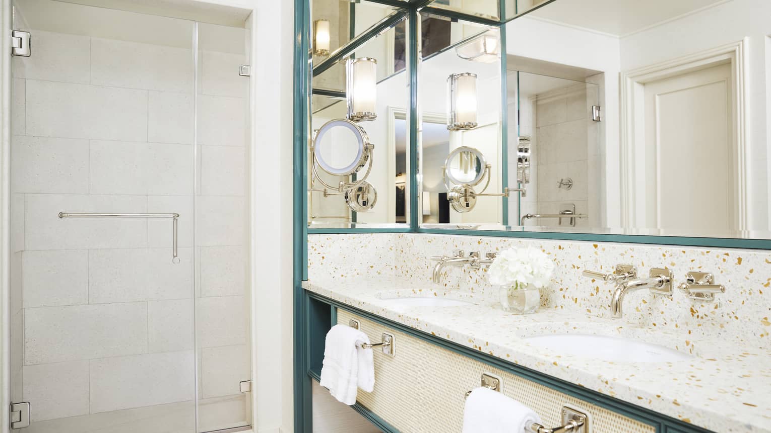A bright bathroom has metal accents and marble countertops