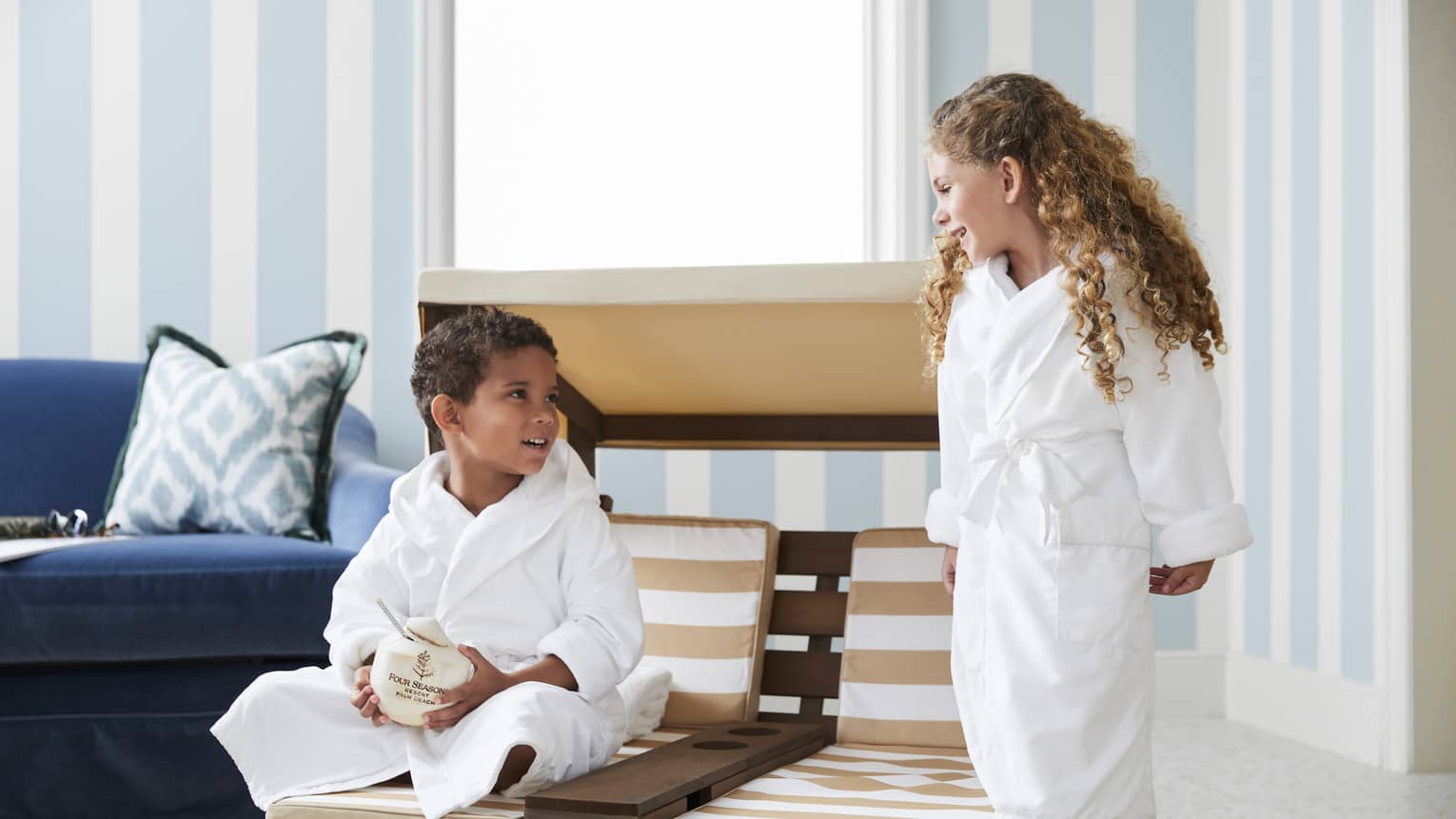 Young guests relax in white robes and enjoy a coconut beverage