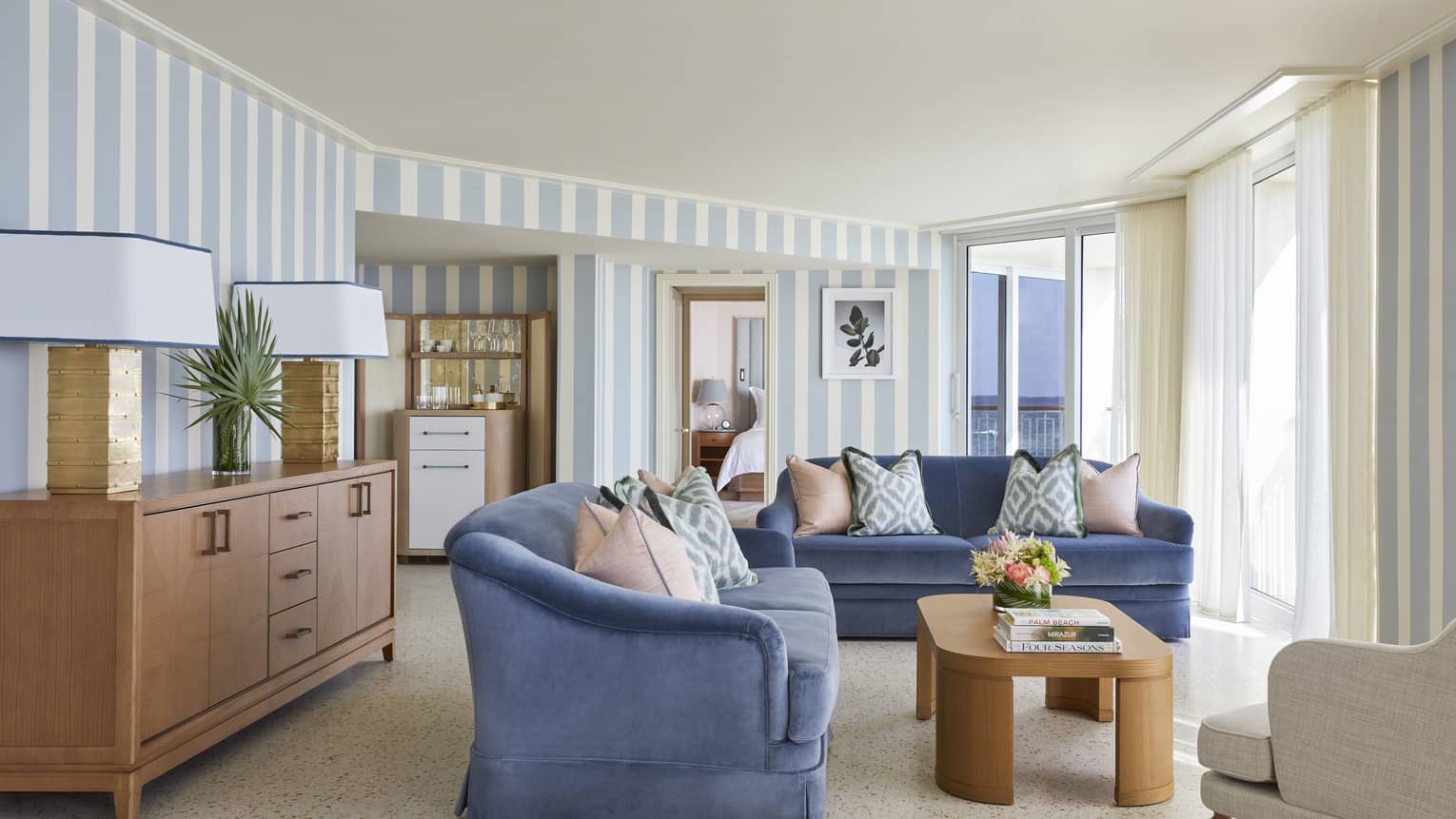Living area in a Sea Breeze Suite, with blue sofas, a coffee table and light blue- and white-striped walls