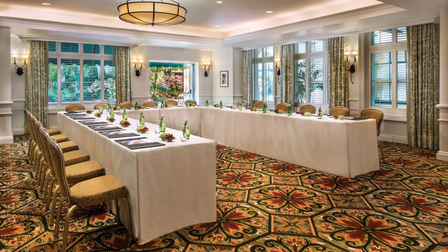 El Jardin carpeted meeting room with modular tables set with water bottles, fresh grapes