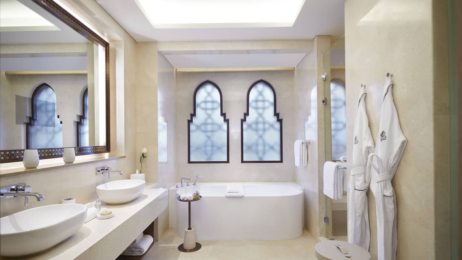 Bathroom with tub, two frosted windows, two sinks and two hanging robes
