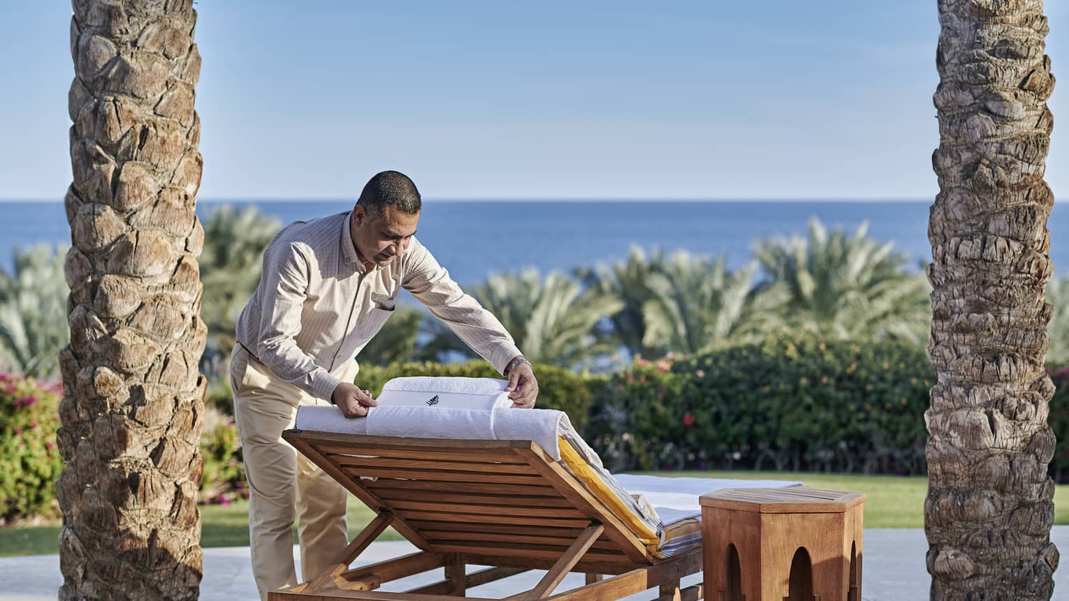 Man arranging a pool chair with sea in background