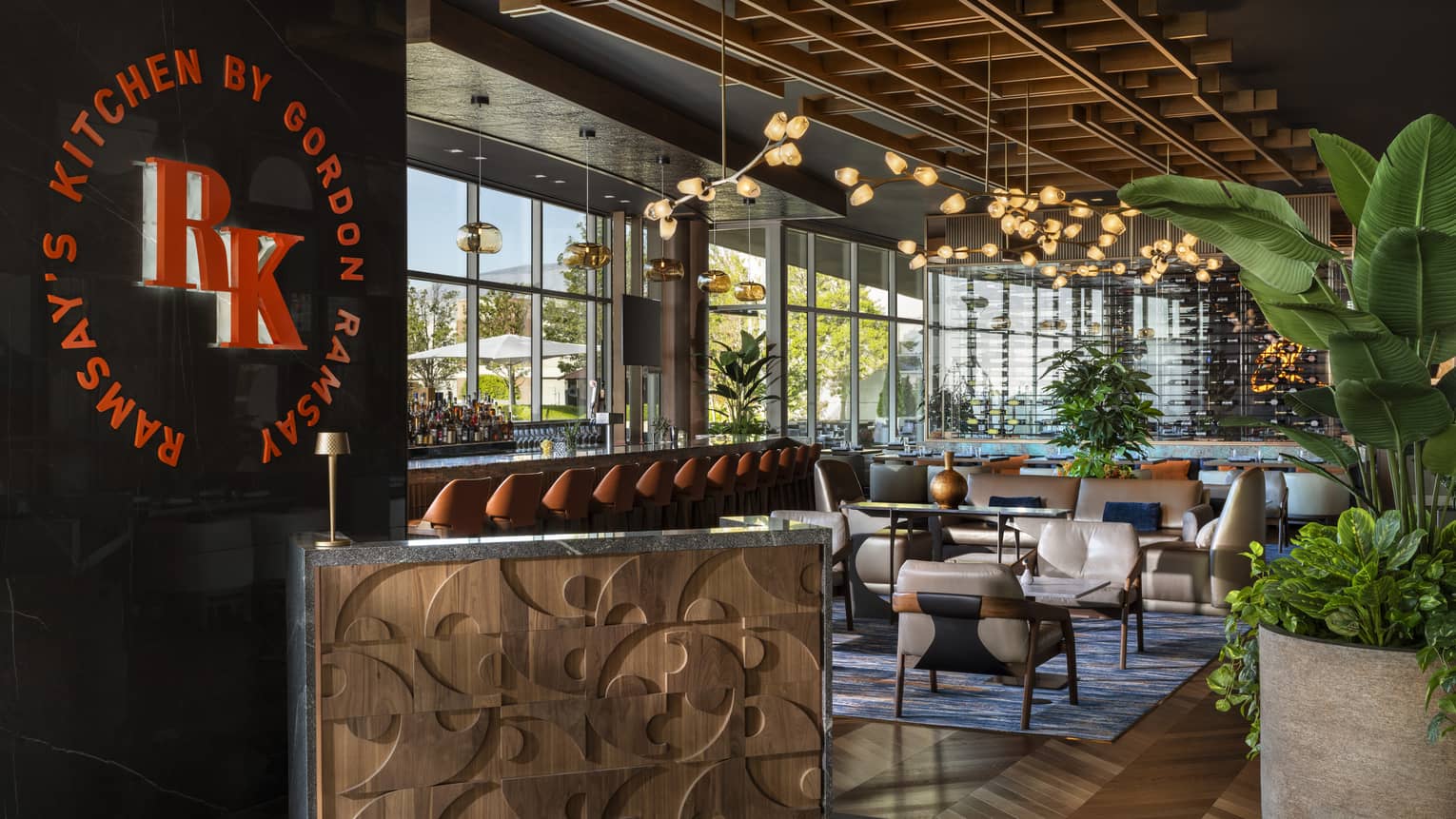 Dining room with large potted plants and suspended lighting at Ramsay's Kitchen by Gordon Ramsay