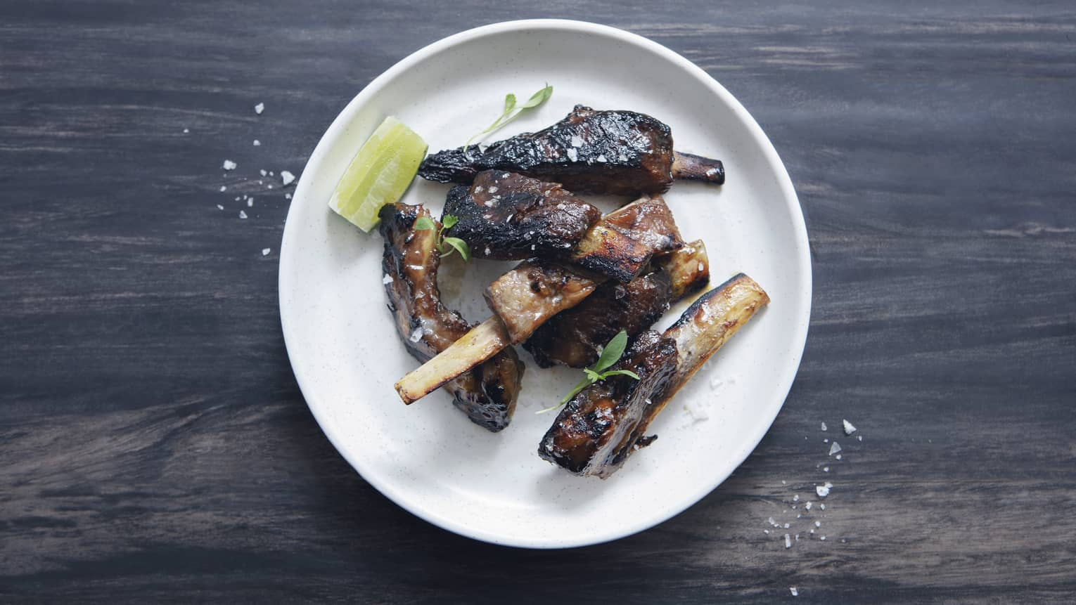 Gourmet barbecue ribs, bones on white plate on wood counter
