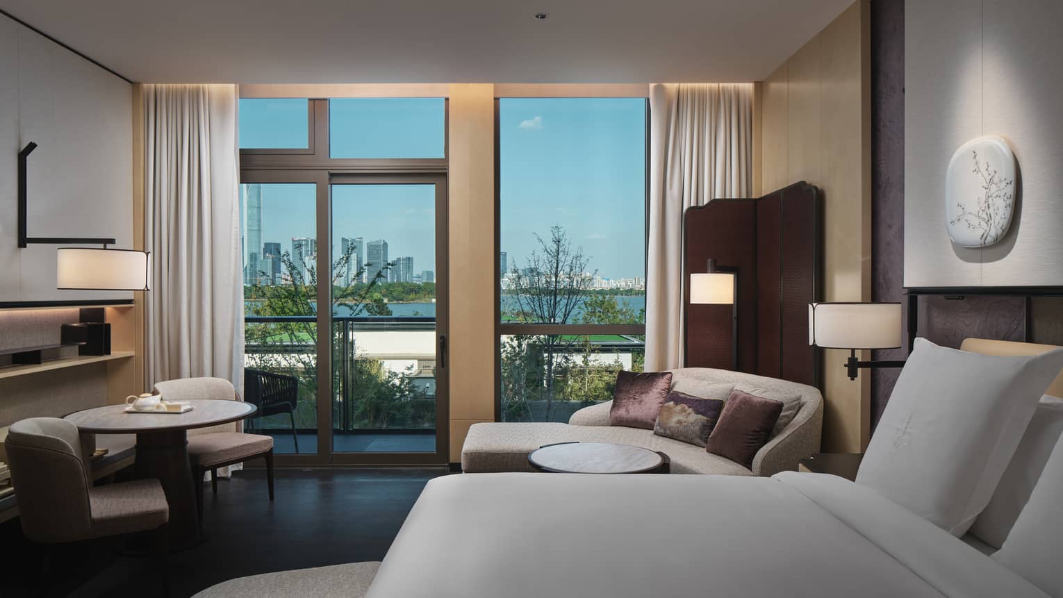 Hotel room with king bed, window-side chaise and view of lake in Suzhou