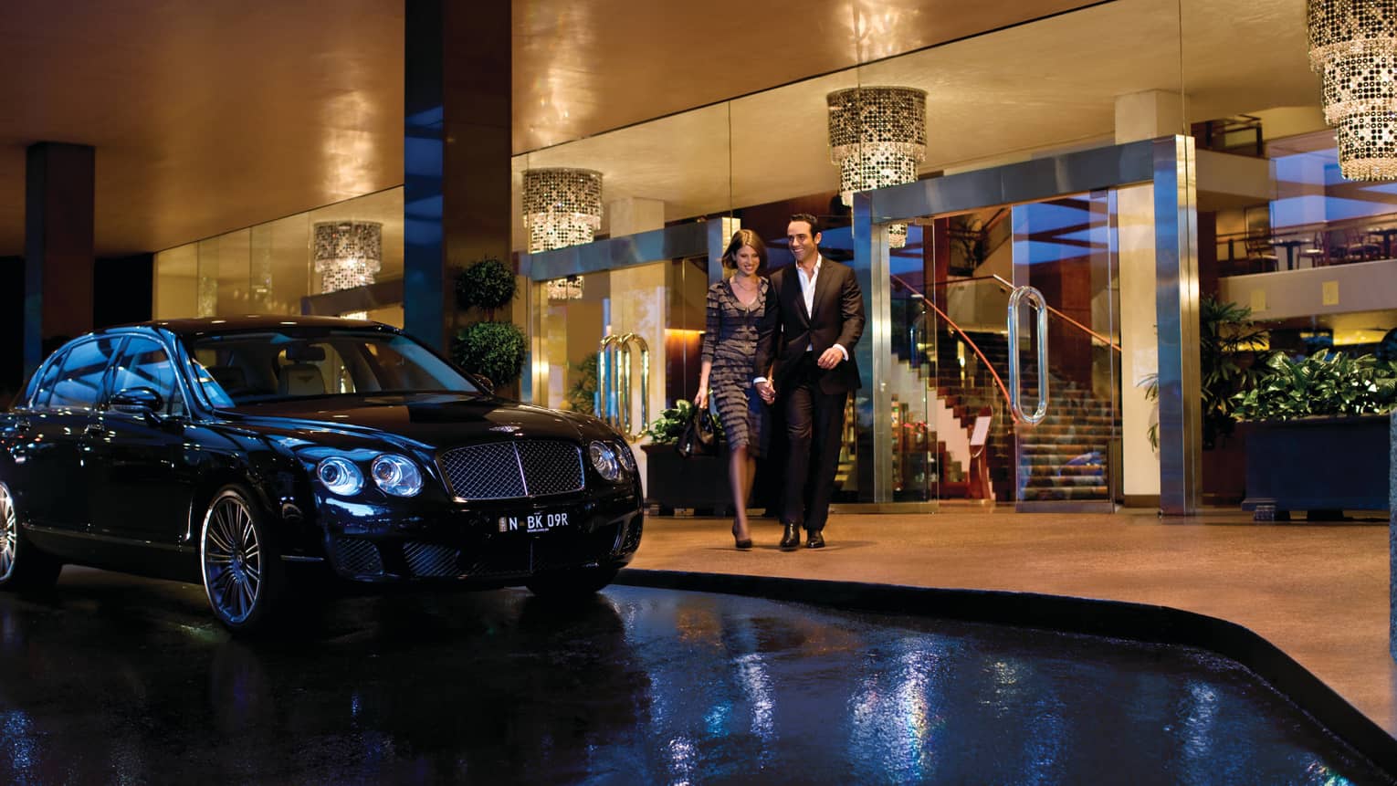 Man and woman walk arm-in-arm past luxury car, Four Seasons Hotel Sydney entrance
