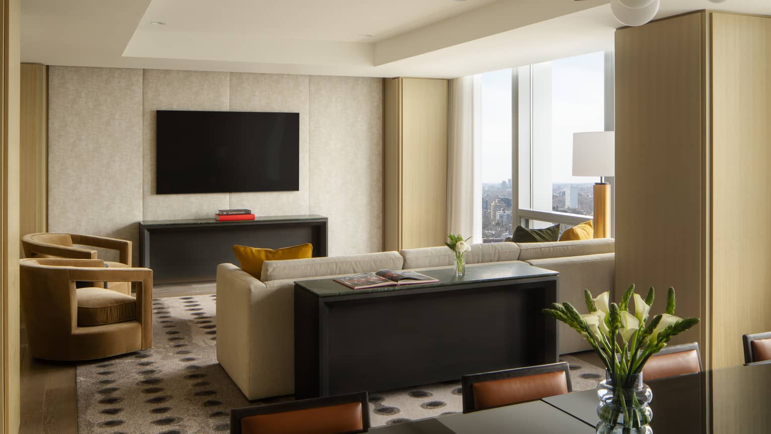 Hotel suite living room with large TV and wall of windows at Four Seasons Hotel Toronto