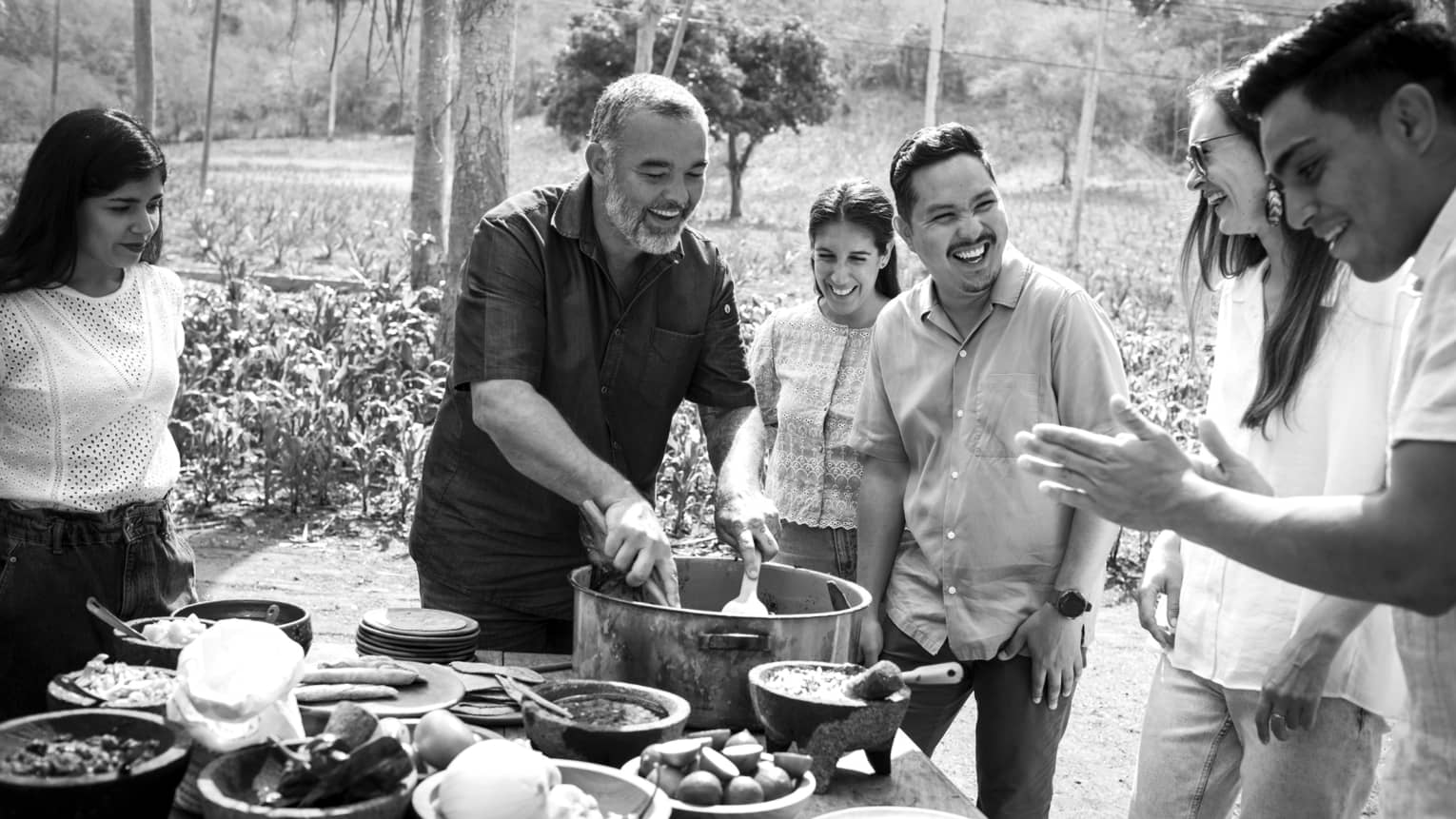A black and white image of a cooking class outside.