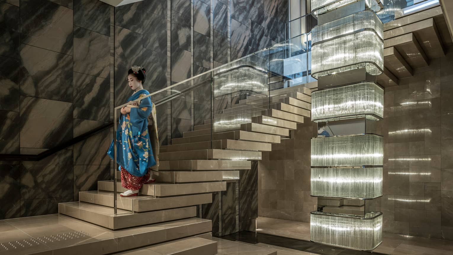 Geisha wearing traditional kimono, make-up descends down marble and glass staircase