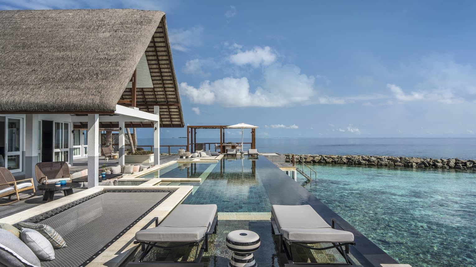 Private pool deck of overwater villa, with overwater lounge net and two chairs