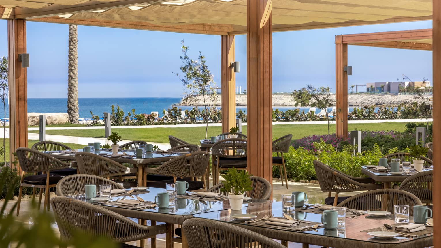 Beach Restaurant covered outdoor terrace with rattan dining chairs and views of the Mediterranean