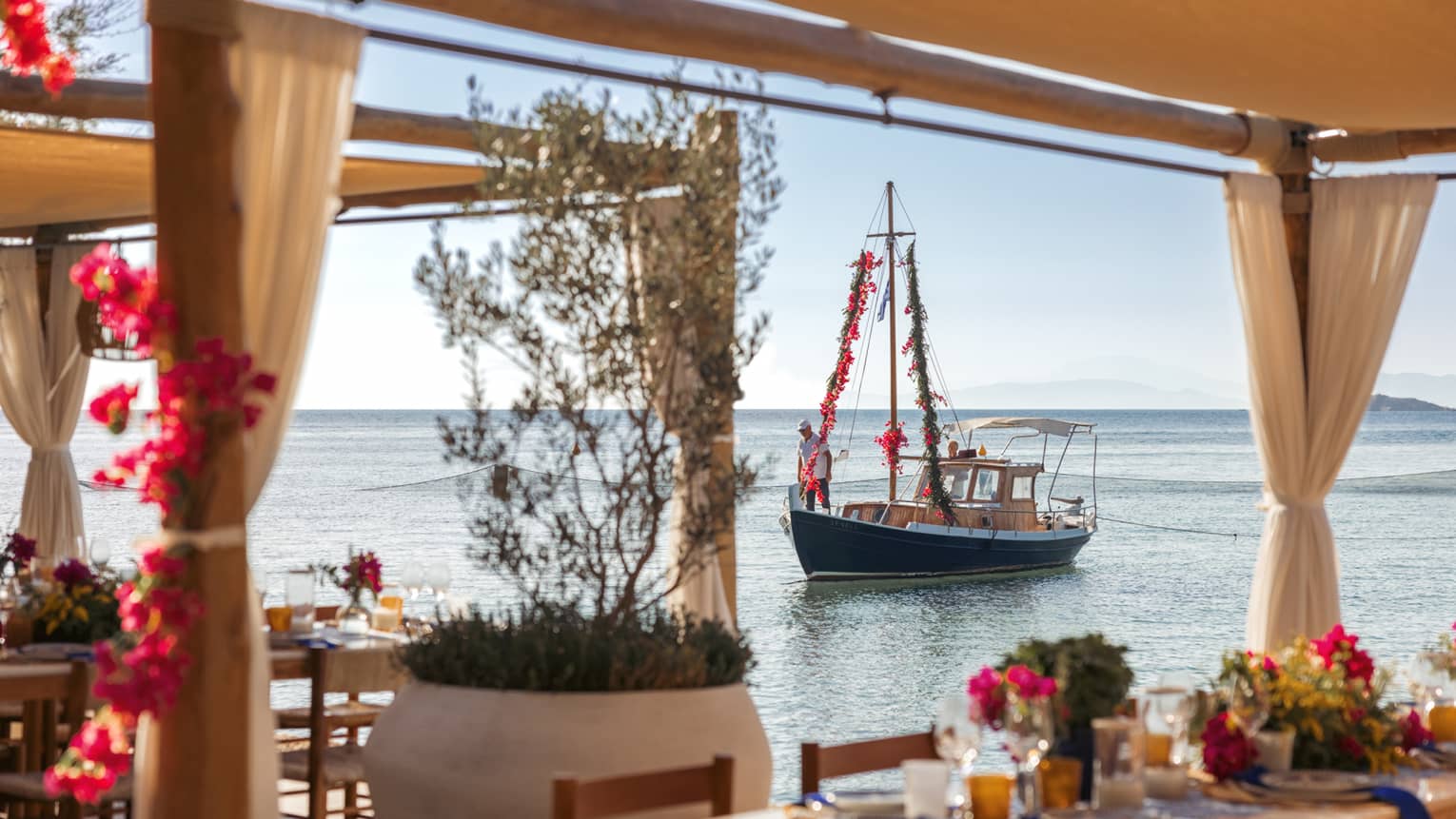 View of sailboat on calm Saronic Gulf through waterfront restaurant patio of Taverna 37