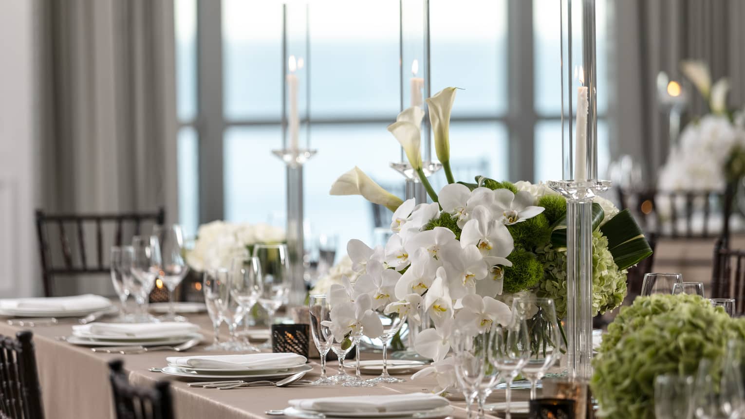 Part of formally set dining table with white orchids and tall crystal candlesticks