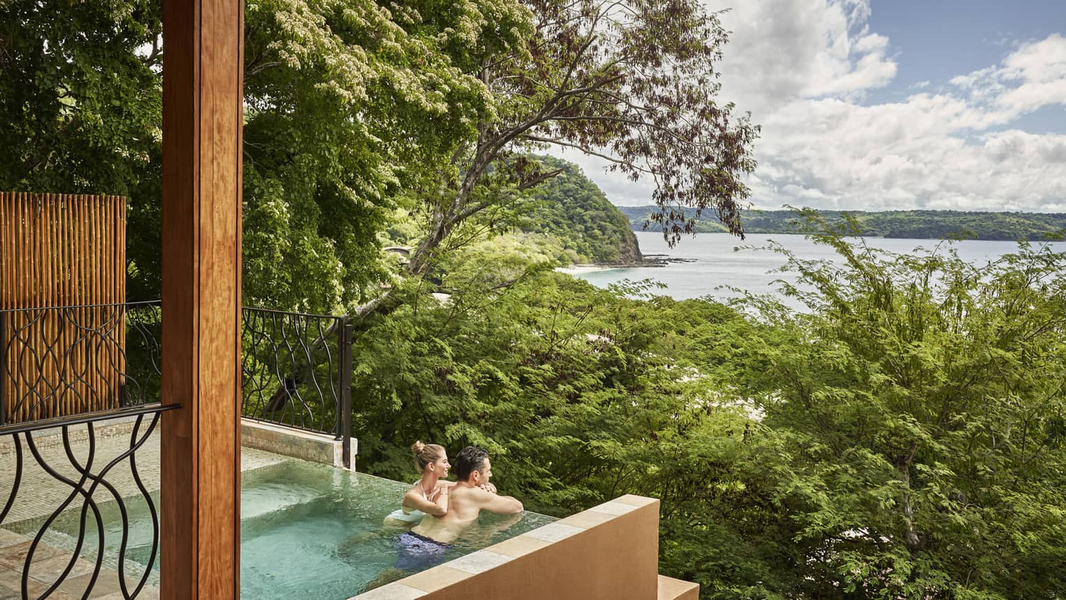 Couple in private plunge pool looking out to trees and ocean