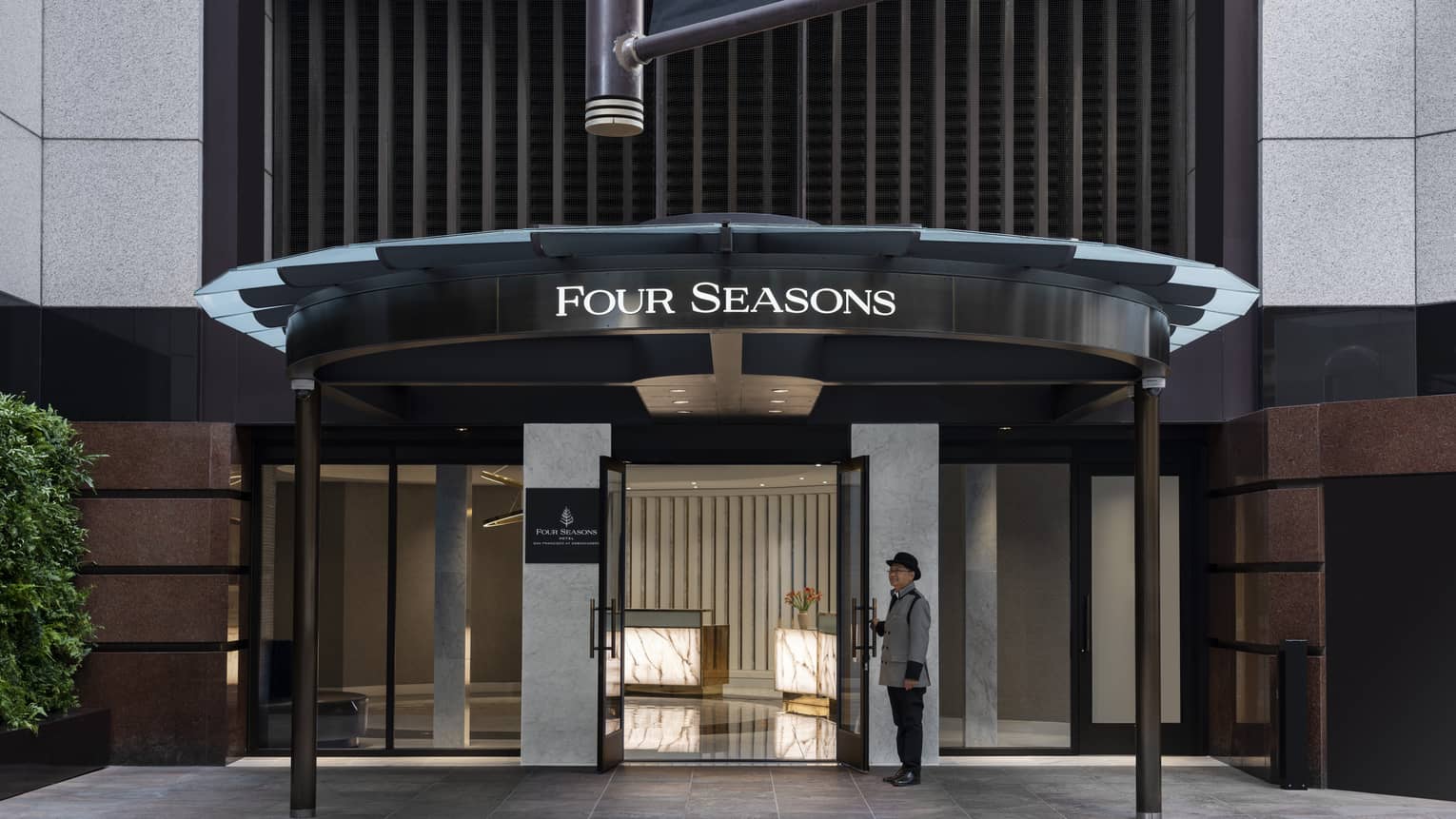 An entrance to a hotel with a team member standing at the door.