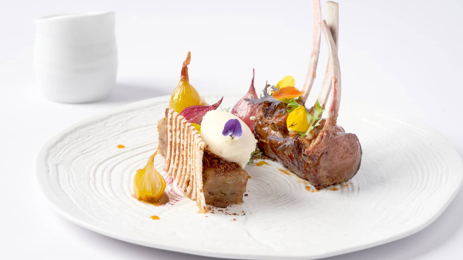 Gourmet rack of lamb topped with candied yellow beets, flowers