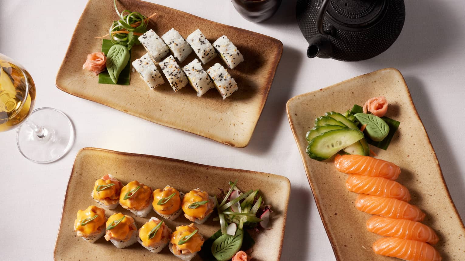 Three rectangular dishes with assorted sushi and sashimi