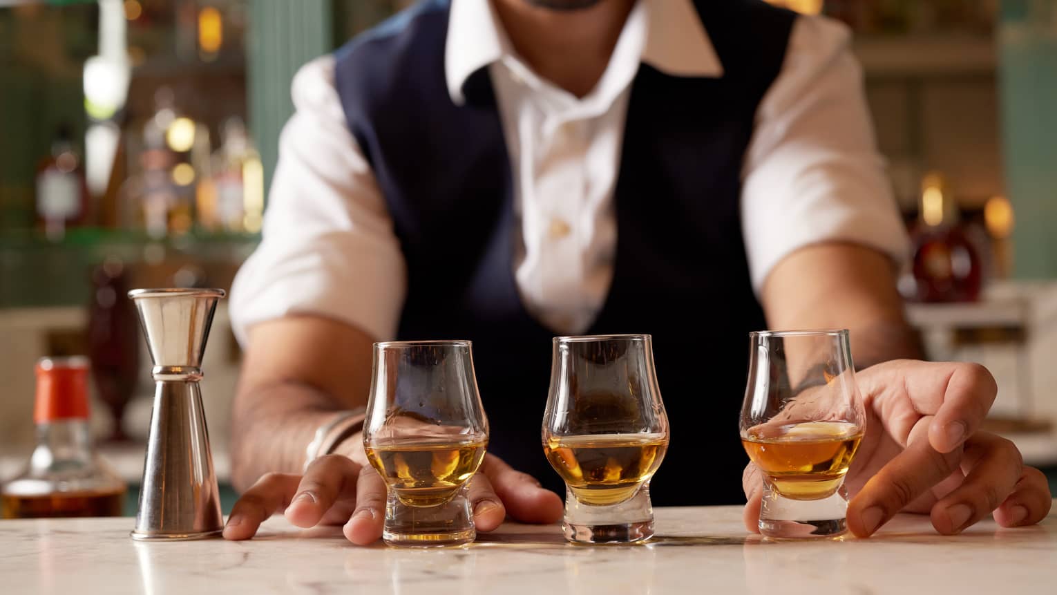 Bartender serving up three snifters halfway full of whisky