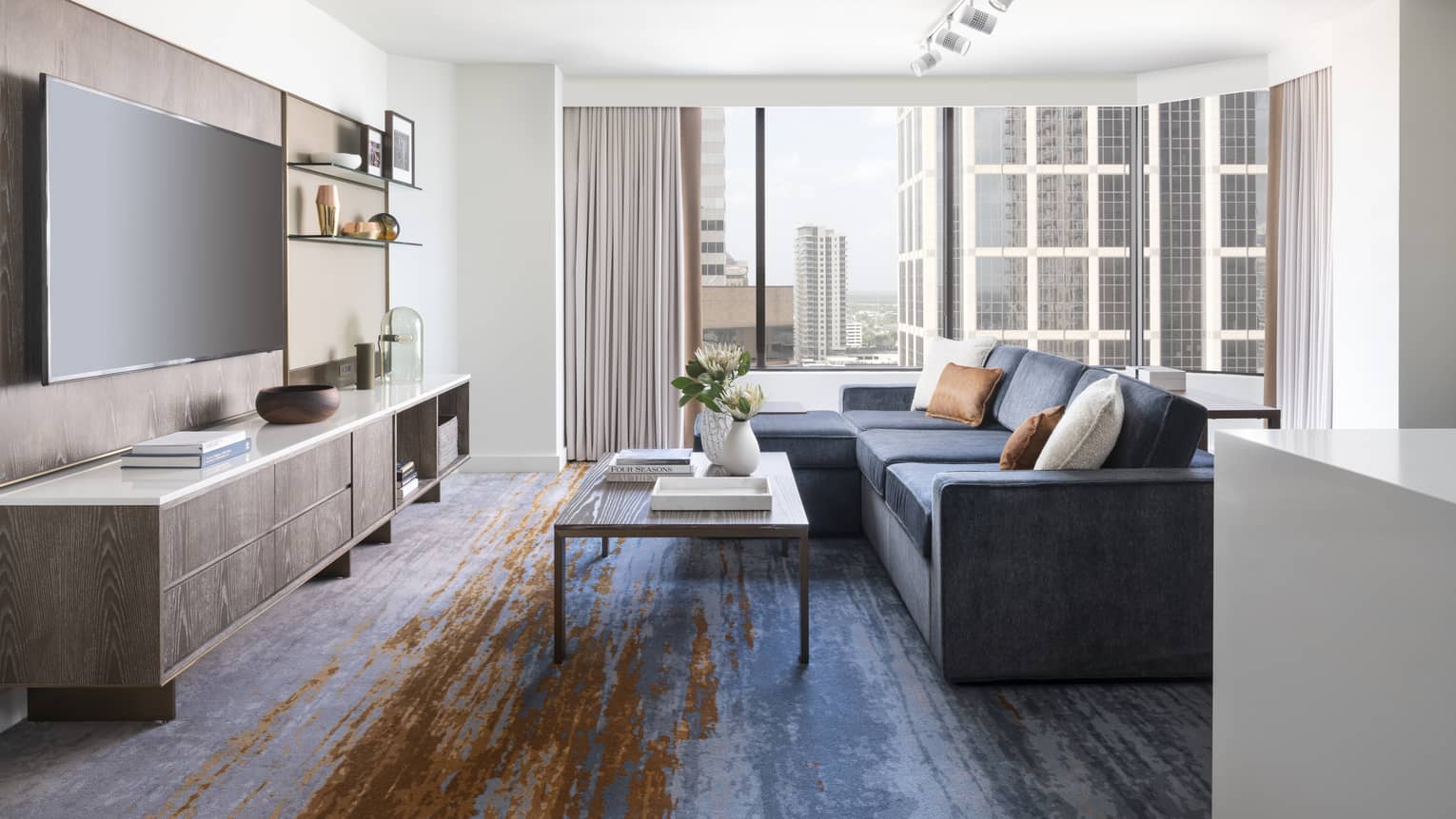 Two-bedroom Residential Suite living area with navy sectional sofa, floor-to-ceiling windows, city views