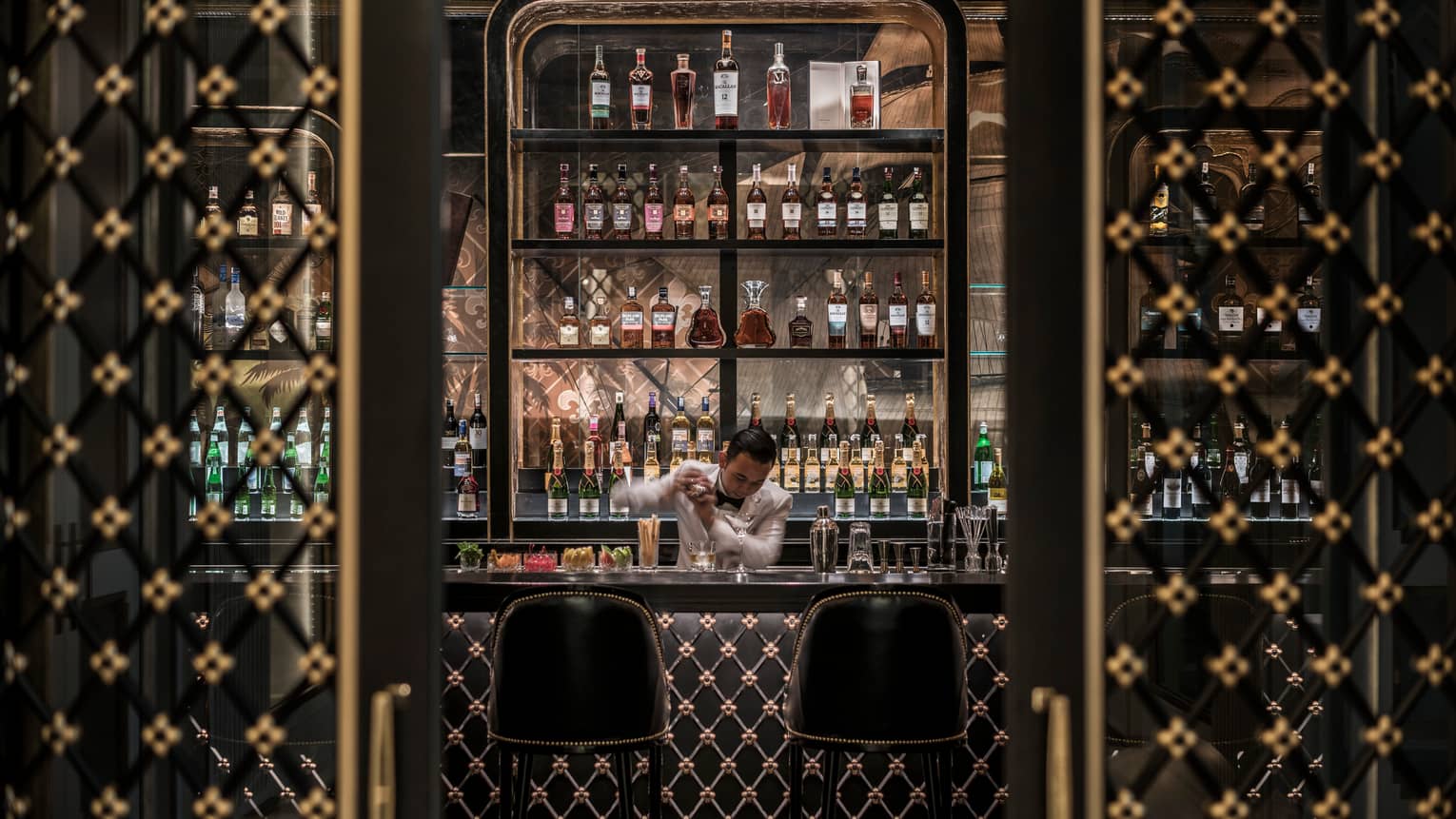 Bartender shakes drink behind dark Nautilus Bar with black-and-gold Art Deco-style design